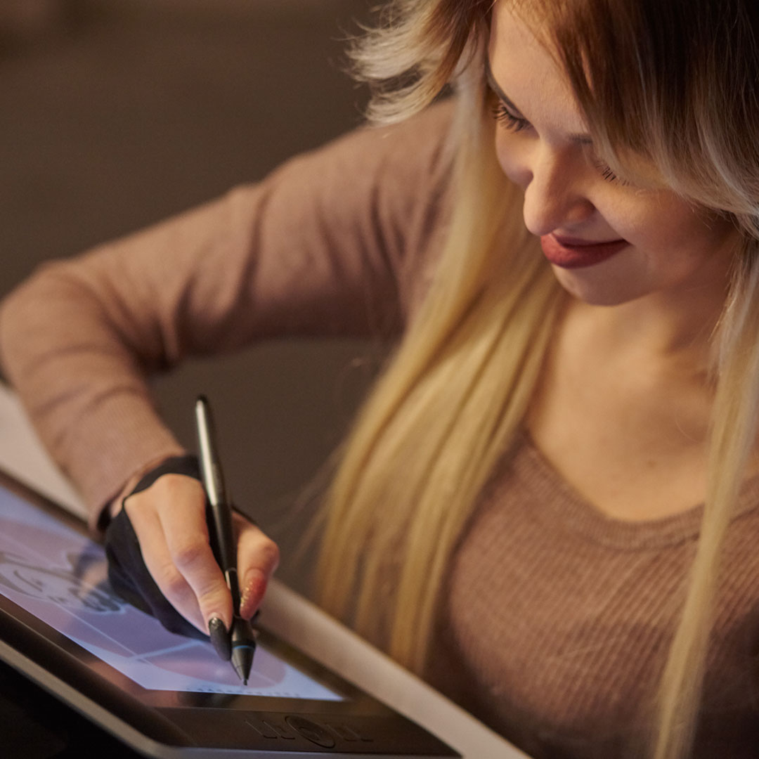 A person drawing on a digital tablet with a stylus while working on an illustration.