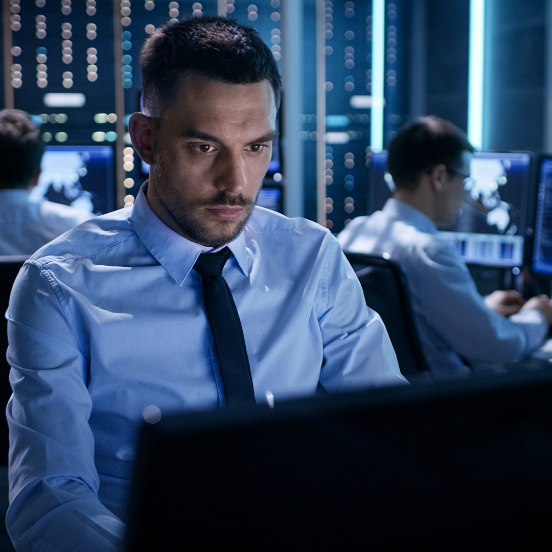 A man in a business suit intently gazes at a computer screen, focused on his work.