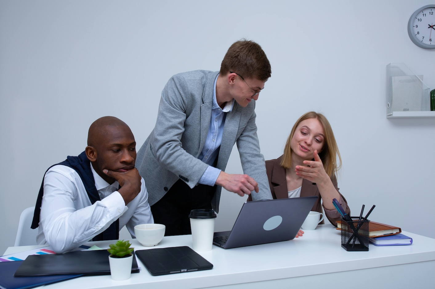 Three engineering professionals collaborating on a laptop in a modern office setting.