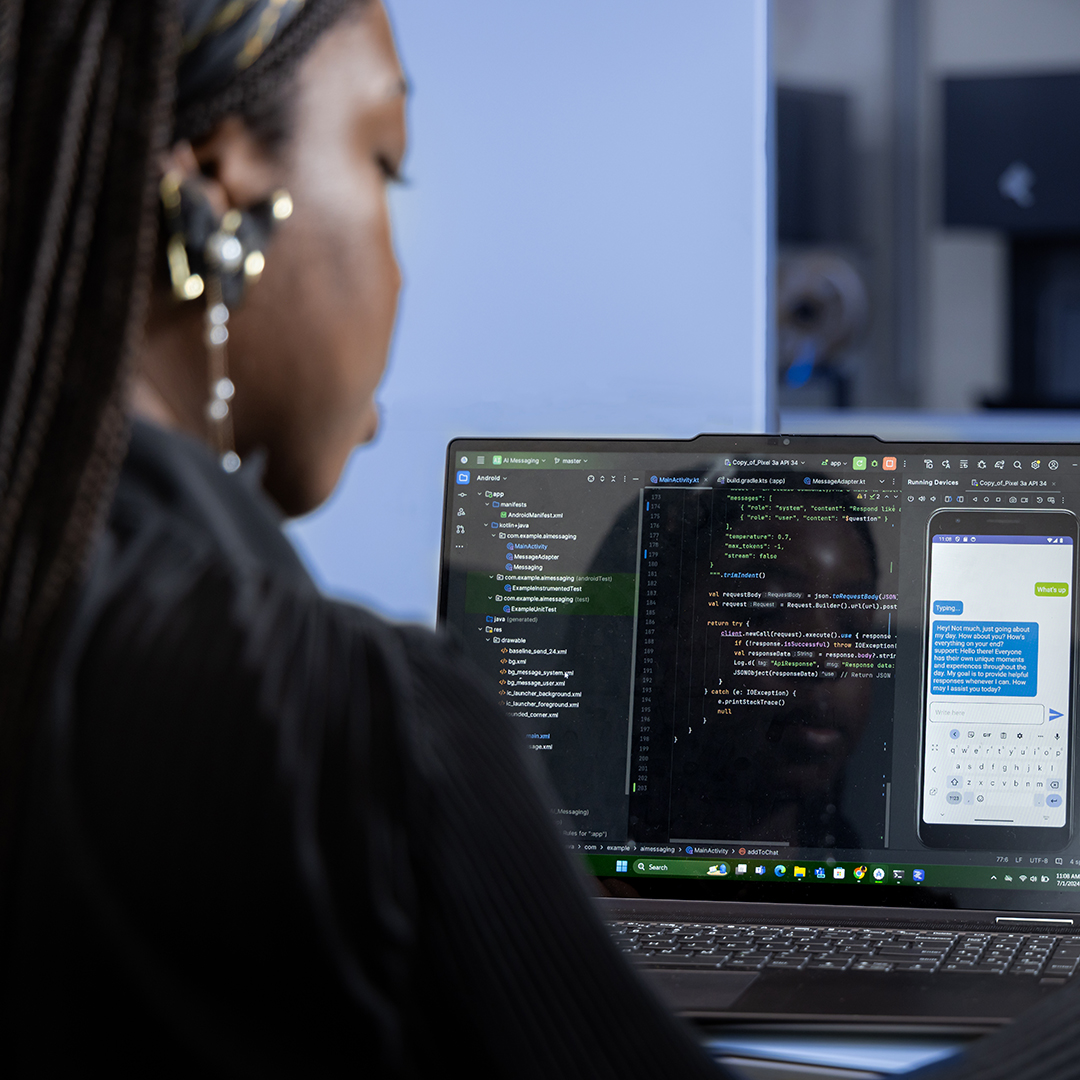 A woman is coding on a laptop that displays a text message.
