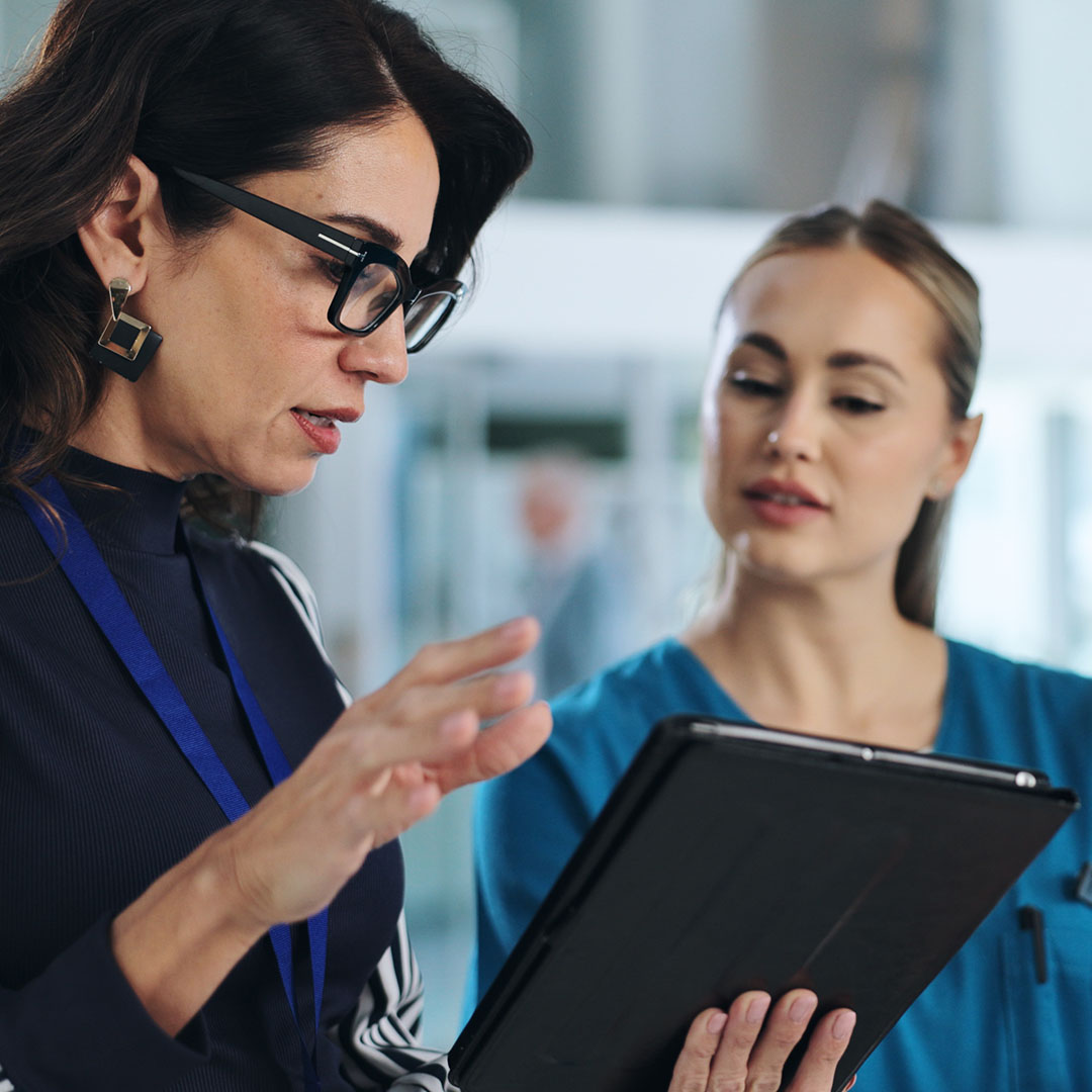 Healthcare professionals engaging in strategic discussion while reviewing information on a digital tablet.