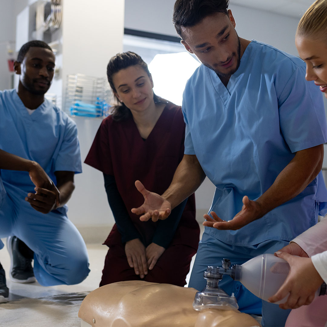 Nursing instructor guiding learners through skill development using clinical simulation equipment.