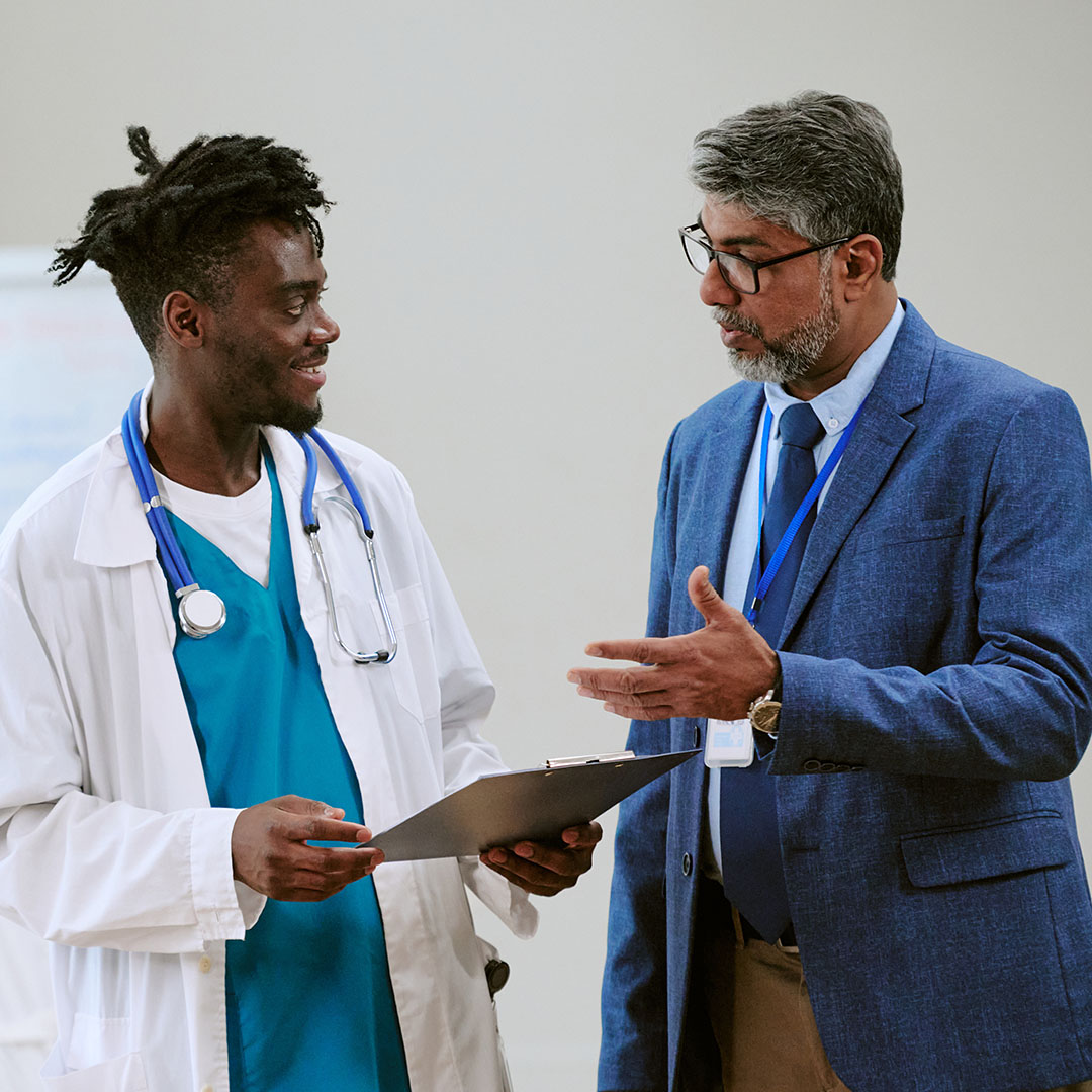 Healthcare professionals reviewing documents and discussing operational decisions in a clinical workplace setting.