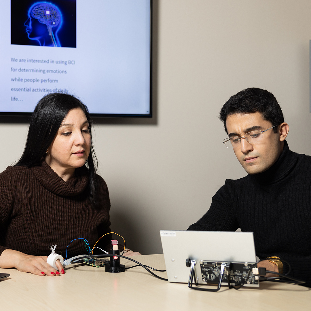 An application developer is testing a sensor on a woman's finger to check her blood glucose level.