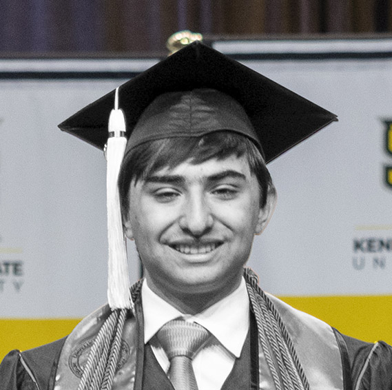 Male student smiles at commencement in cap and gown