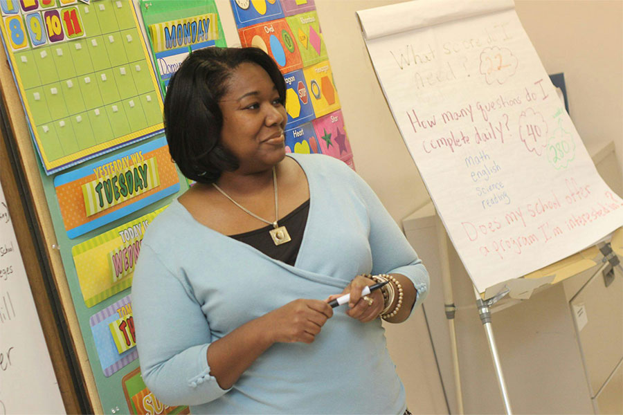 african american teacher at board teaching elementary students