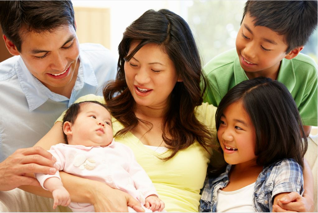 A family of four holding a new baby