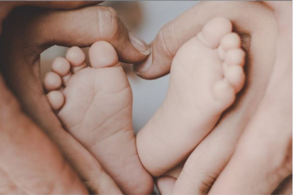 Parents hands holding their babies feet to create a heart symbol