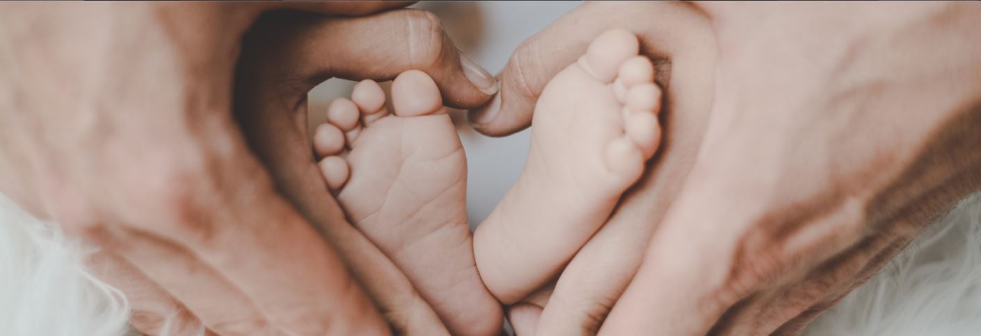 hands in a heart shape around infant feet