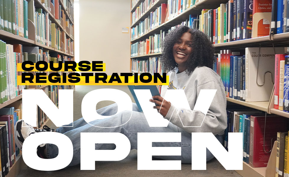 Smiling female student sitting on the floor between stacks of books - overlay text reads Course Registration Now Open.