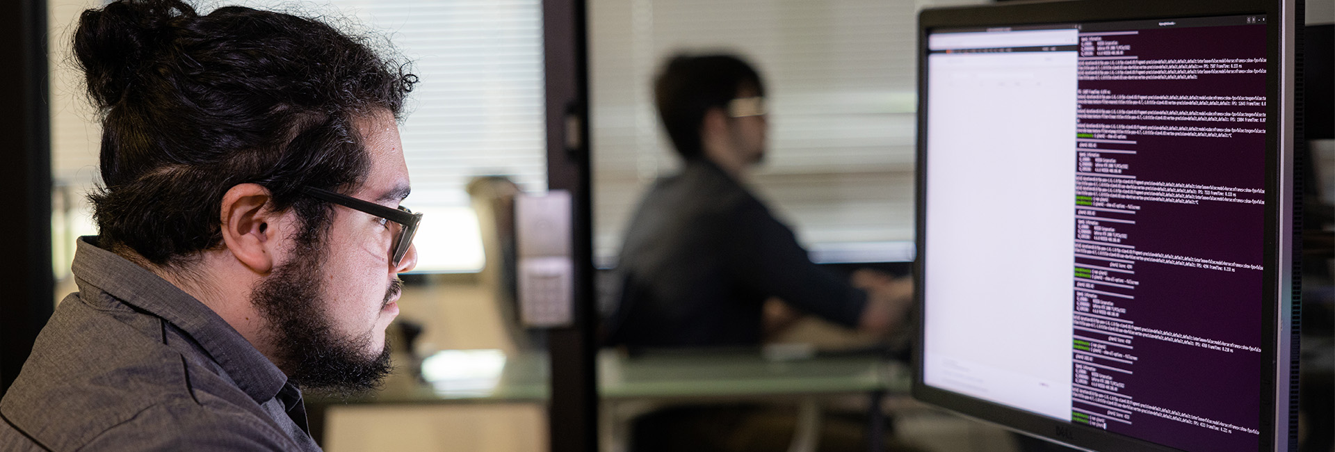 two men sitting at computer with data on screen