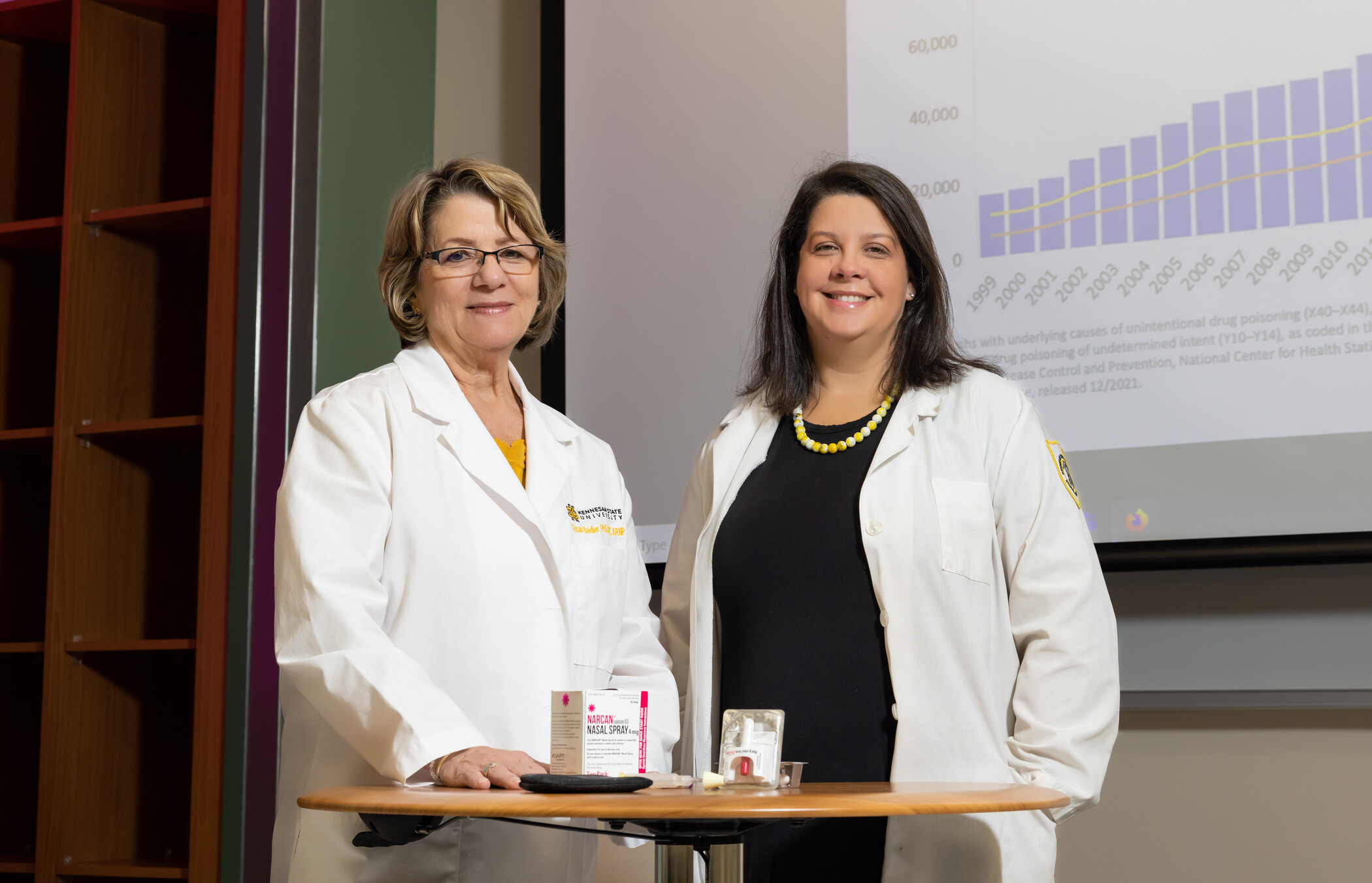 two research professionals smiling in white lab coats