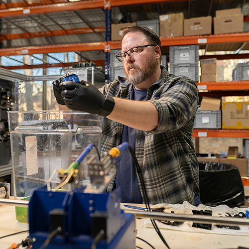 man with beard in plaid shirt working in a shop