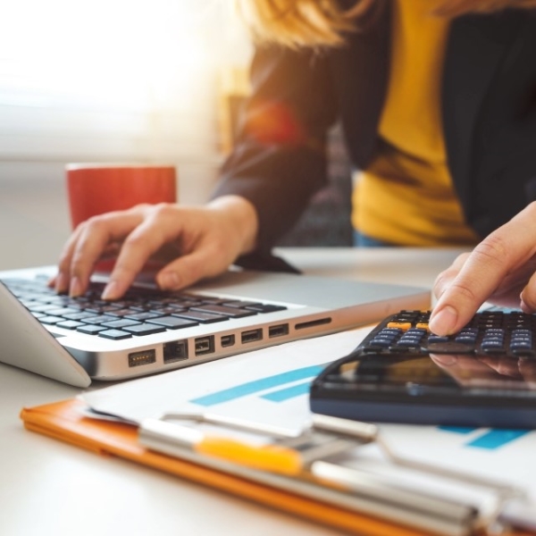 Image of a woman typing on a laptop and using a calculator 