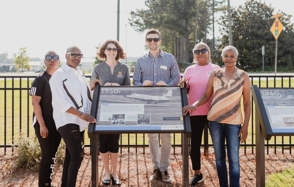 a group of people standing around a historical information sign