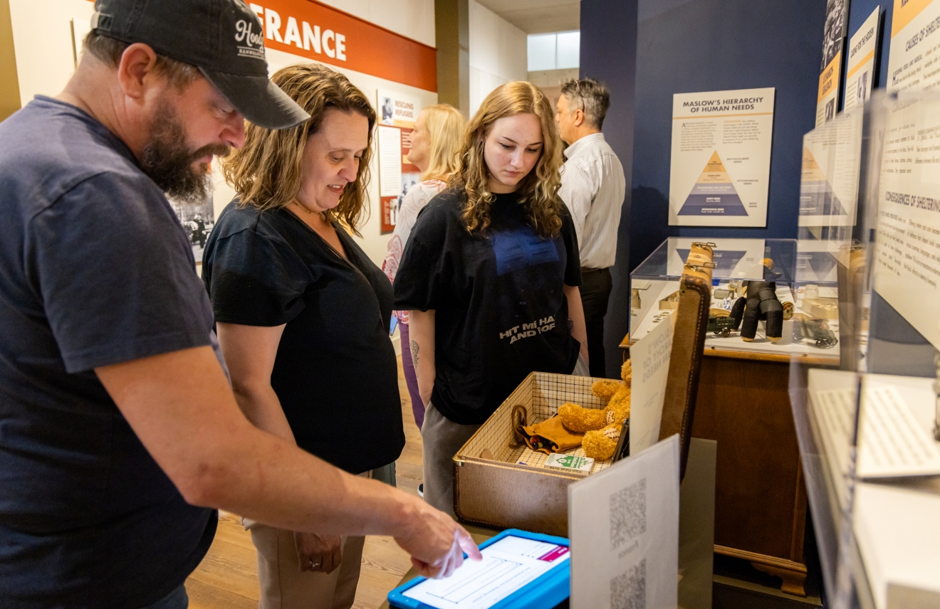 Several museum visitors looking at items in teh exhibittion