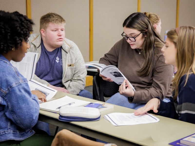Four teachers sitting at a table discussing workshop materials