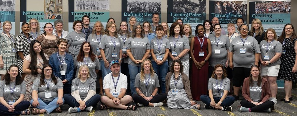 A group photo of professional development workshop participants infront of museum panels