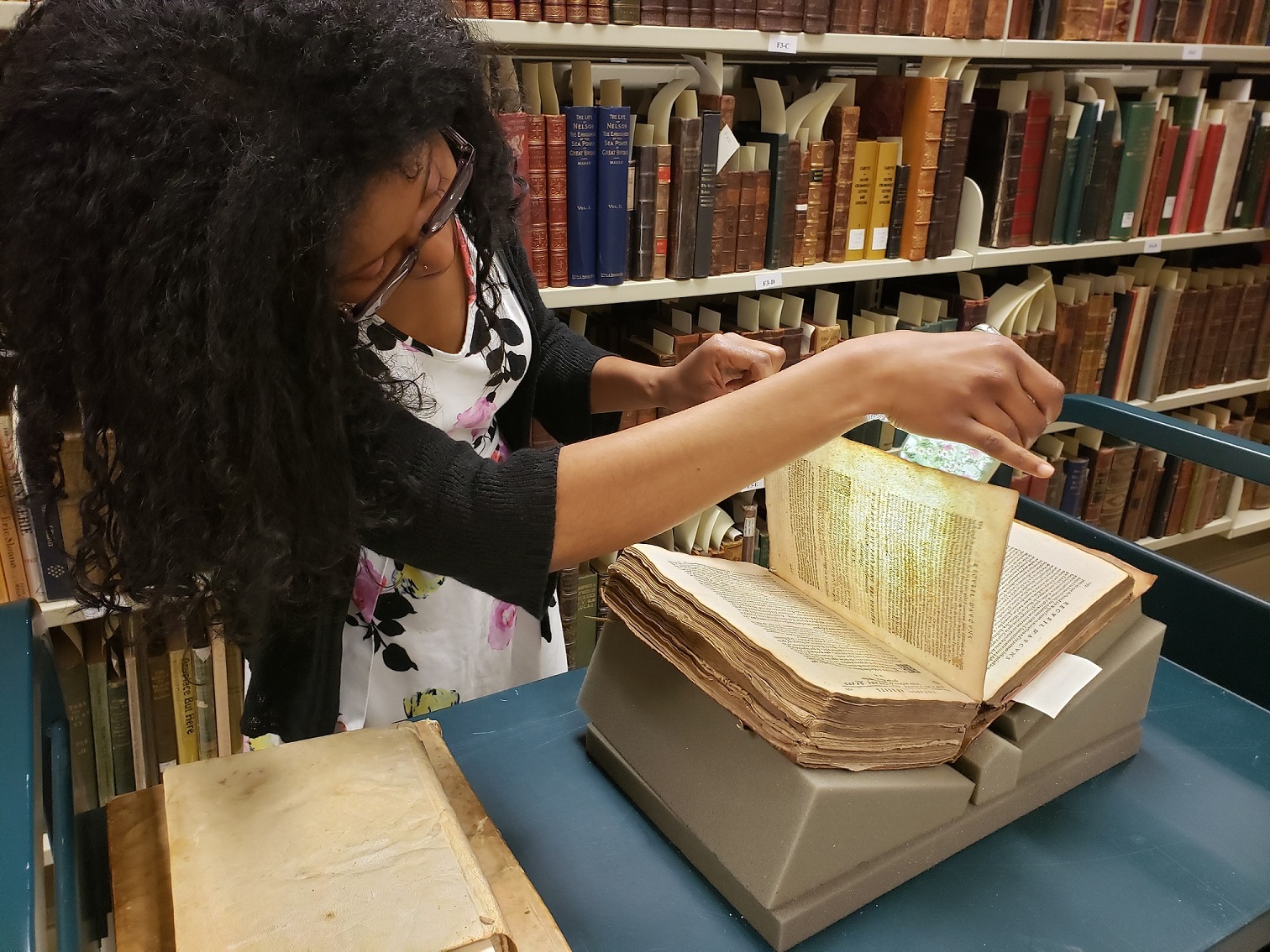 Curator JoyEllen Williams examining a rare book in the Bentley Rare Book Museum.