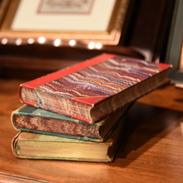 A stack of 3 old books on a desk