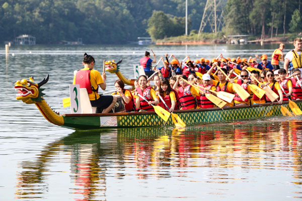 Lots of people rowing a dragon boat in the water.