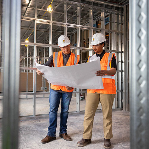 two construction students looking at blue prints for a project.