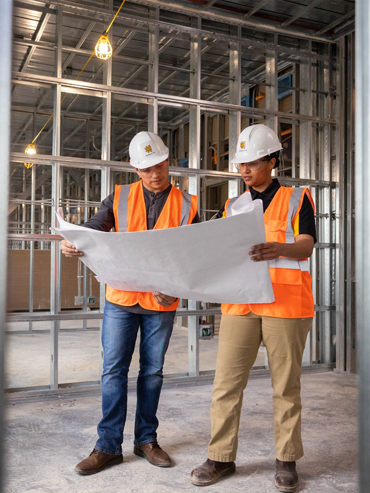 two construction students looking at blue prints for a project.