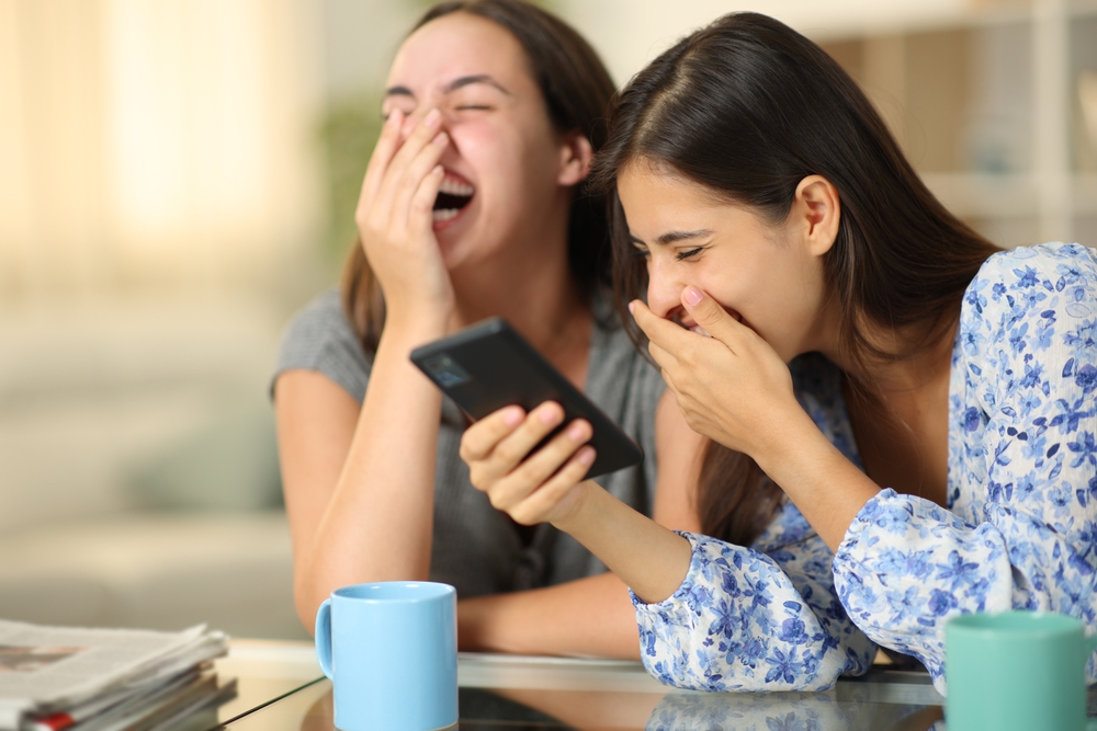 Two ladies looking at a smartphone and laughing