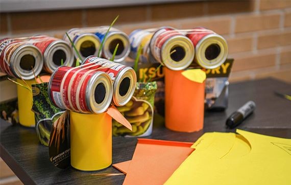 A table with owls sitting on it, that were created using cans and paper.