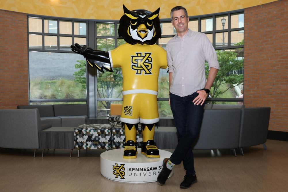  / Marcelo Medeiros poses for a portrait with a statue of Scrappy at Kennesaw State University in 2025.