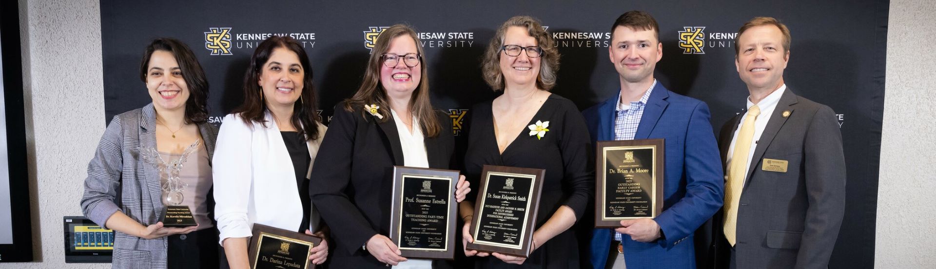 Group of faculty members holding awards with the text 'Our Faculty Matter(s)' overlaid on the image.