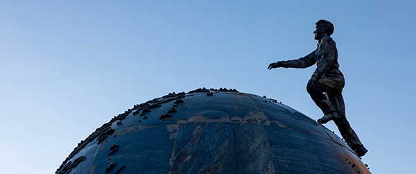 man walking to top of globe statue on campus