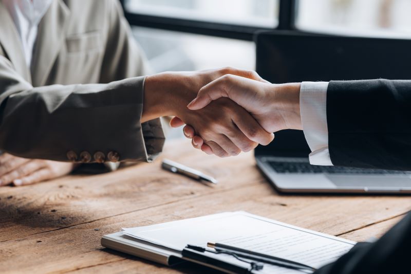 Two hands shaking in an office setting.