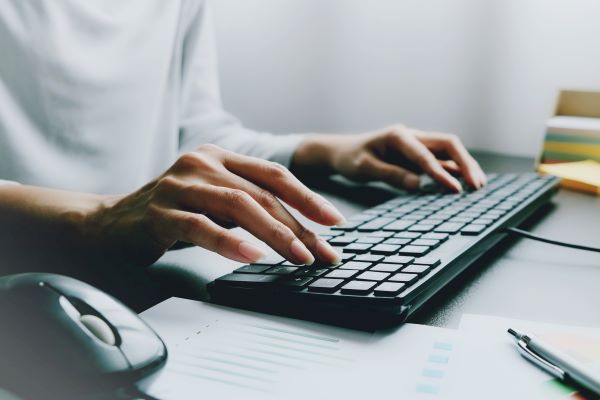 Hands of a woman typing on a keyboard