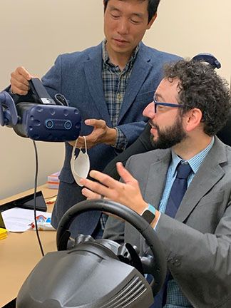 Two professionals testing a VR headset with a driving simulator.