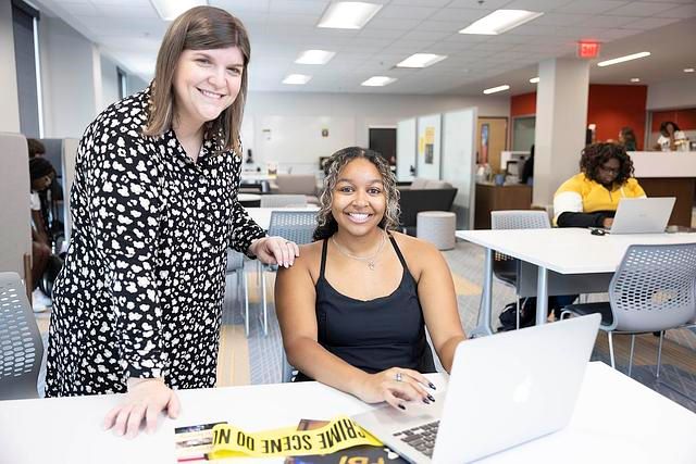 An advisor mentoring a student using a laptop.