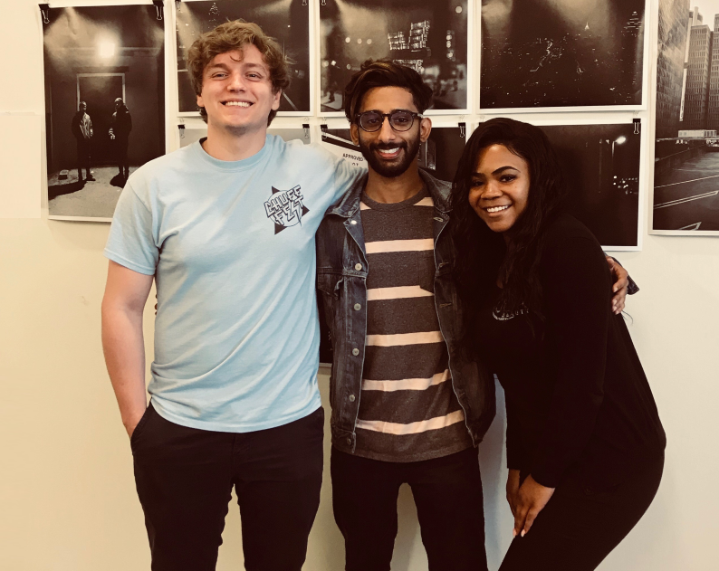 Center for Sustainable Journalism’s student experiential learning graduates in front of a Bokeh_Focus photo gallery display.
