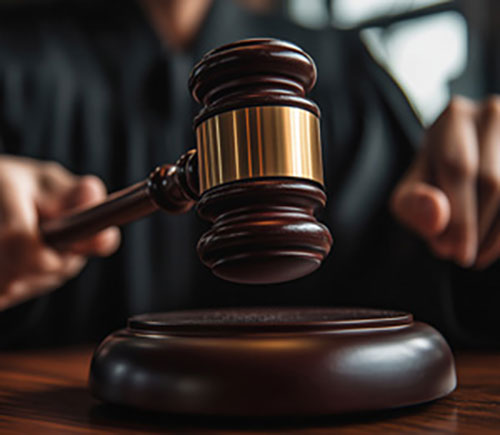 A wooden table supports a judge's gavel, representing the judicial process in criminal justice.