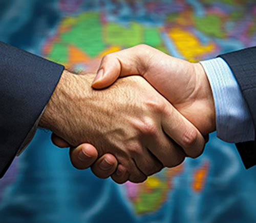 A handshake between two business individuals before a world map, representing efforts in international conflict resolution.