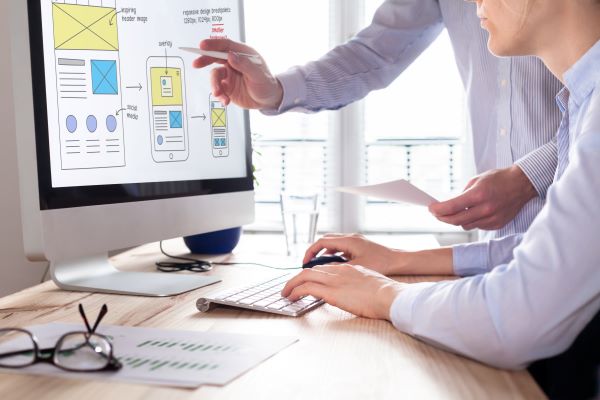 Two people collaborating on a UI/UX design project on a computer screen.