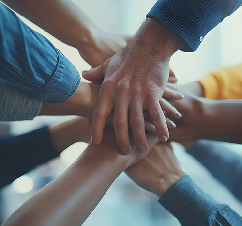 A diverse group of individuals joining hands, symbolizing unity and collaboration in workplace interpersonal relationships.