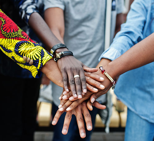 A diverse group of individuals standing together, their hands joined in a display of unity and collaboration.