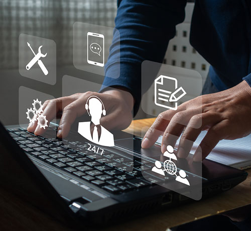 An individual typing on a laptop, which features multiple icons, symbolizing a connection to technology and information.