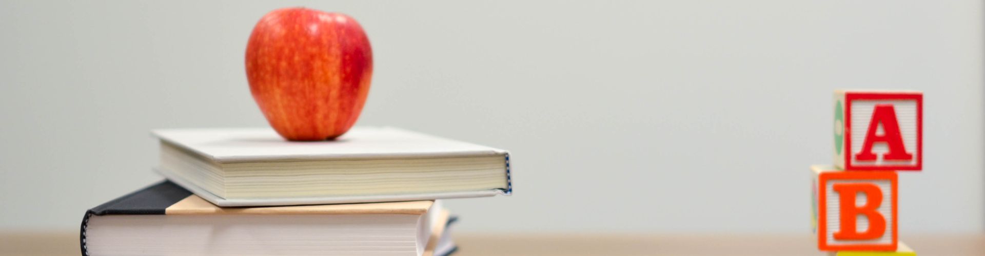 Apple on top of stack of books with letter building blocks