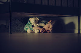 child wih teddy bear hiding in the dark
