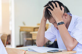 stressed man with hands on head looking down at desk