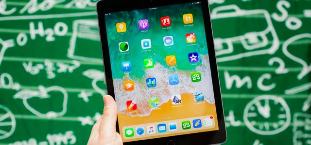 Hand holding an ipad, with a green background.