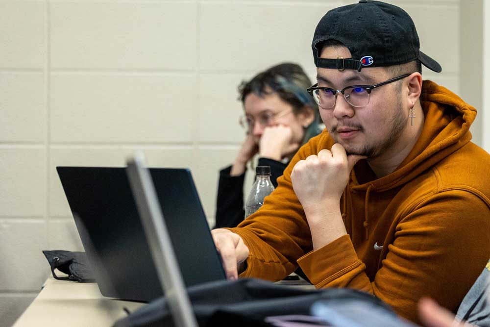young male college student studying on laptop