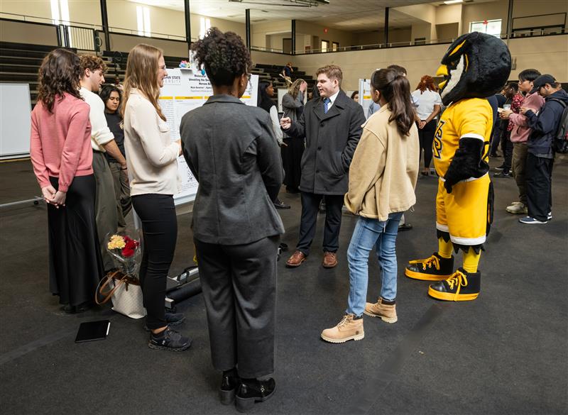 Students standing at presentation with Scrappy owl