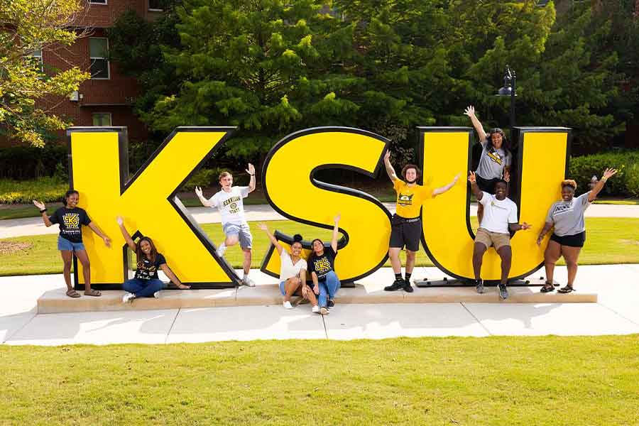 Group of KSU students taking a picture by the KSU sign.